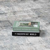 Close-up of the light gray Eltham Thick Luxe Rug with stacked books on top. Styleshot