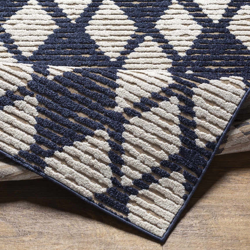 Close-up of the Enhaut 3D Outdoor Area Rug showing its bone and cloud gray geometric pattern and textured, machine-woven construction. Fold