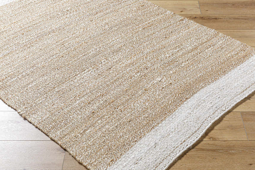 Close-up of the hand woven Aderyn Jute Area Rug. Camel and pearl tones with a subtle stripe detail. Farmhouse style. Corner