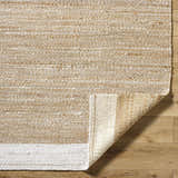 Close-up of hand-woven Aderyn Jute Area Rug showing camel, pearl, and tan colors and textured detail. Fold