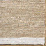 Close-up of the Aderyn Jute Area Rug showing the camel and pearl hand-woven texture and jute material. Corner