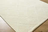 Close-up of the off-white Almeda Washable Wool Area Rug showing its hand-tufted texture and diamond pattern. Corner
