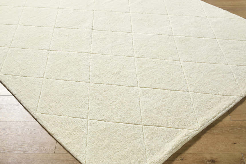 Close-up of the off-white Almeda Washable Wool Area Rug showing its hand-tufted texture and diamond pattern. Corner