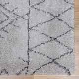 Close-up of a Flintville Moroccan Shag Area Rug. Charcoal geometric pattern on a light beige, shaggy pile. Swatch