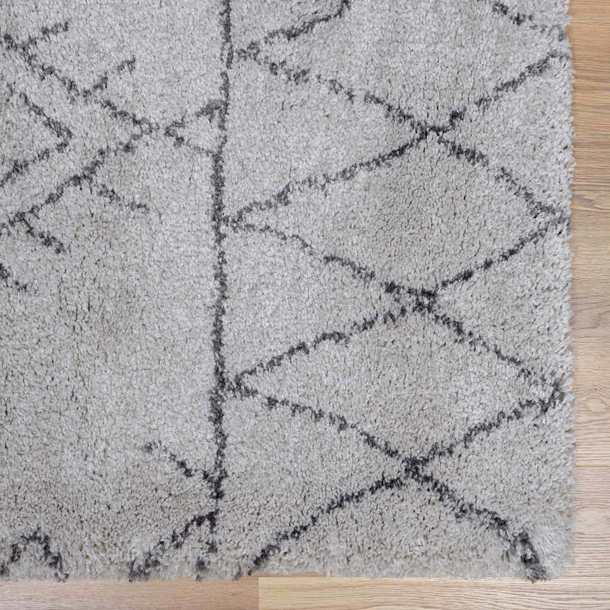Close-up of a Flintville Moroccan Shag Area Rug. Charcoal geometric pattern on a light beige, shaggy pile. Swatch