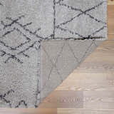 Close up of the Flintville Moroccan Shag Area Rug showing the charcoal diamond pattern, plush texture, and rug backing. Fold