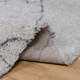 Close-up of the Flintville Moroccan Shag Area Rug showing its charcoal and light beige pattern and soft, shaggy texture. Fold