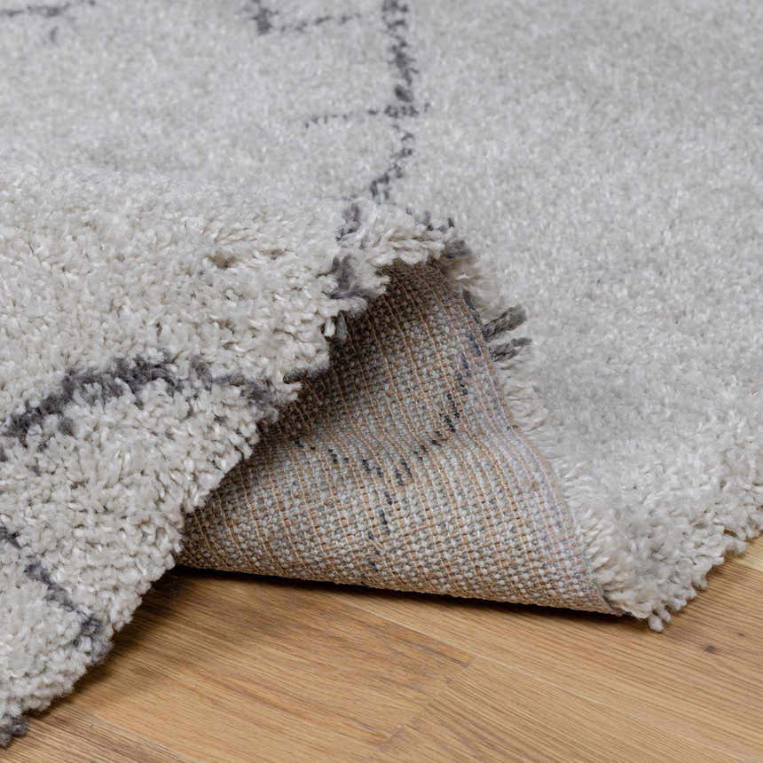 Close-up of the Flintville Moroccan Shag Area Rug showing its charcoal and light beige pattern and soft, shaggy texture. Fold