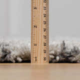 Close-up of the plush pile height of the Flintville Moroccan Shag Area Rug in charcoal and light beige, measured in inches. Pile