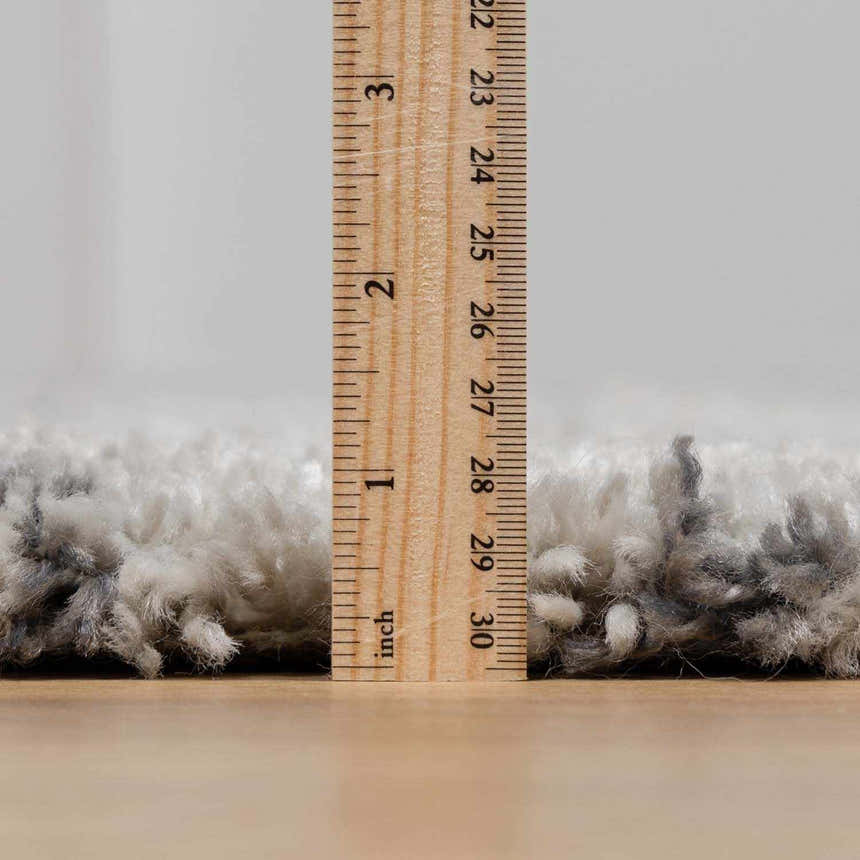 Close-up of the plush pile height of the Flintville Moroccan Shag Area Rug in charcoal and light beige, measured in inches. Pile