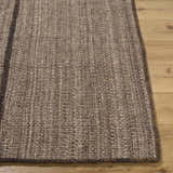 Close-up of the hand woven texture of the Lisua Global Modern Wool Area Rug in neutral brown tones on wood floor. Front