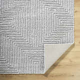 Close-up of the Ashlyn Light Slate Area Rug showing its gray geometric shag design and durable machine-woven construction. Fold