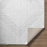 Close-up of the Ashlyn Cream Area Rug showing its shag texture and geometric pattern on wood flooring. Fold