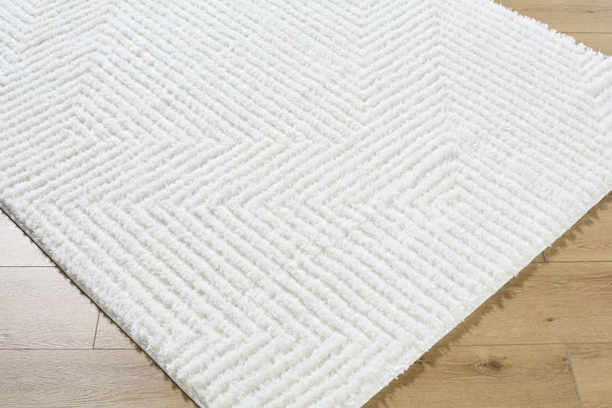 Close up of the cream Ashlyn White Area Rug with a subtle chevron shag design on light wood floors. Corner