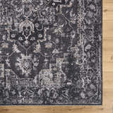 Close-up of the Alissa Black Area Rug showing its traditional, distressed black, gray, and ivory pattern on wood floor. Corner