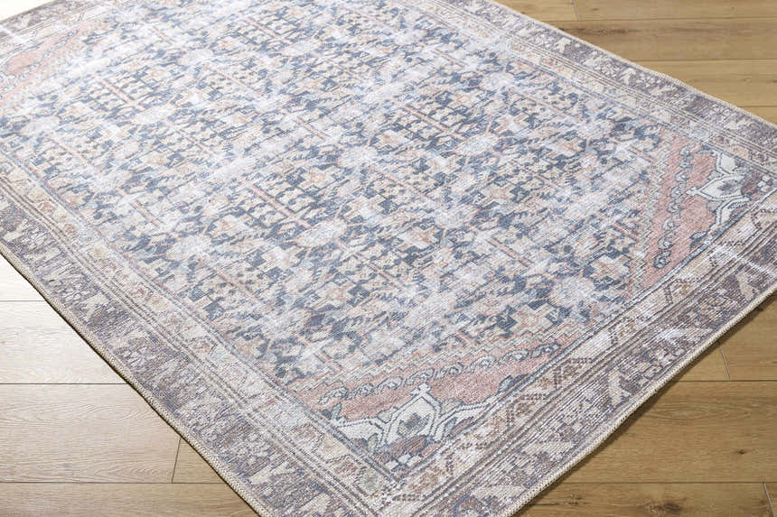Close-up of the Ameera Washable Area Rug featuring a traditional, beige, black, and blue pattern on a wood floor. Corner