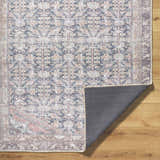 Close-up of the Ameera Washable Area Rug showing its traditional beige, black, and blue pattern and non-slip backing. Fold