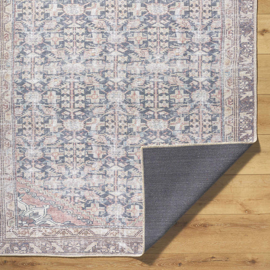 Close-up of the Ameera Washable Area Rug showing its traditional beige, black, and blue pattern and non-slip backing. Fold