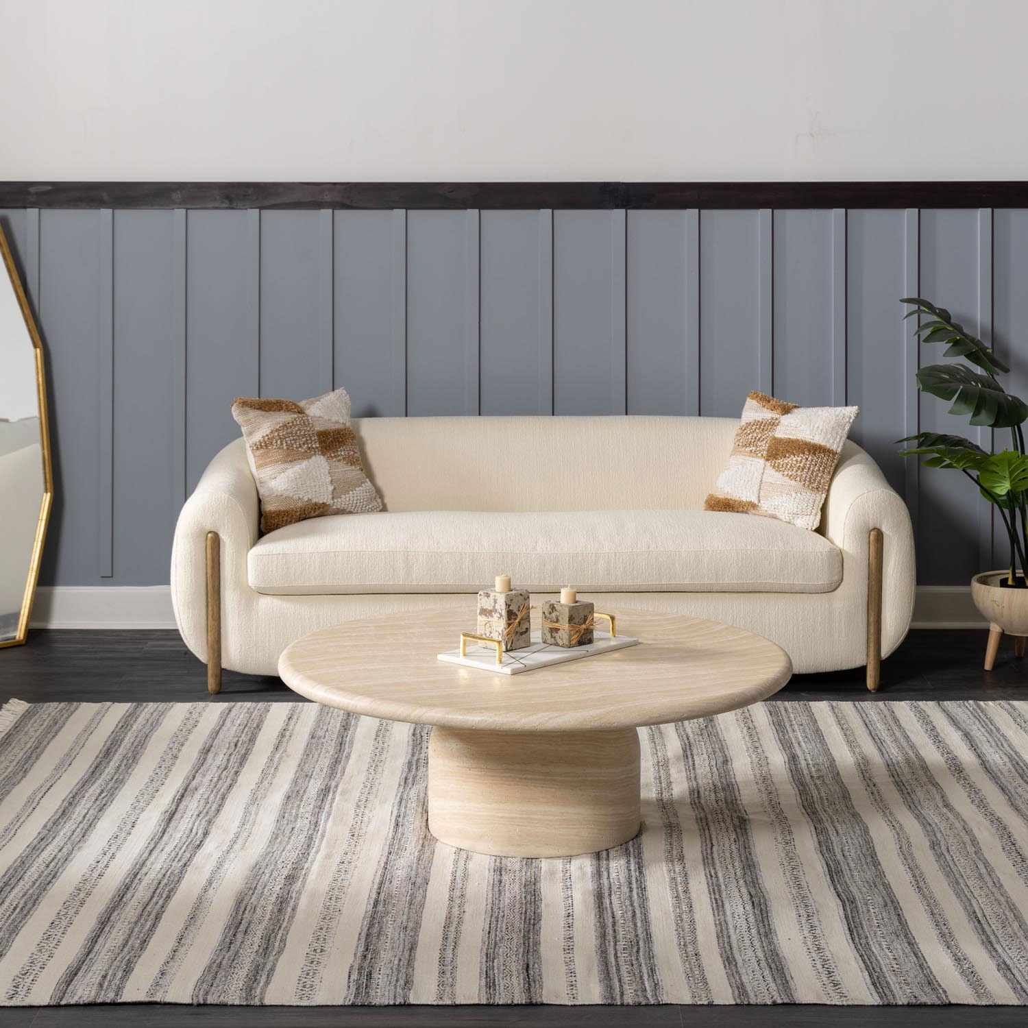 Living room scene with striped Geographe Indoor & Outdoor Rug, cream sofa, round coffee table, and gray paneled wall. Roomscene-Rectangle