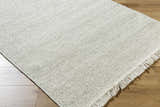 Close-up of the Sorell Sage rug. Textured weave in ecru, ivory, and sage. Wool rug with fringe detail. Corner