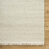Close-up of the Sorell Sage Rug showing its textured weave, ecru and sage colors, and wool fringe. Corner