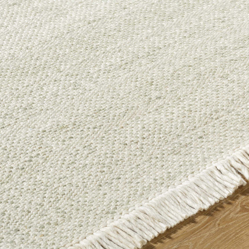 Close-up of the textured weave and fringe of the Sorell Sage Wool Area Rug. Ecru, ivory, and sage tones. Texture