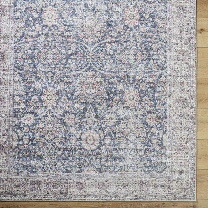 Close-up of the Mary Machine Woven Vivir x LIVABLISS rug. Features beige, black, red, and brown traditional floral patterns. Corner