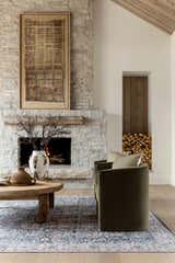 Living room scene with stone fireplace, olive chairs, and the Mary Machine Woven Vivir x LIVABLISS VVMR-2300 Area Rug. Styleshot