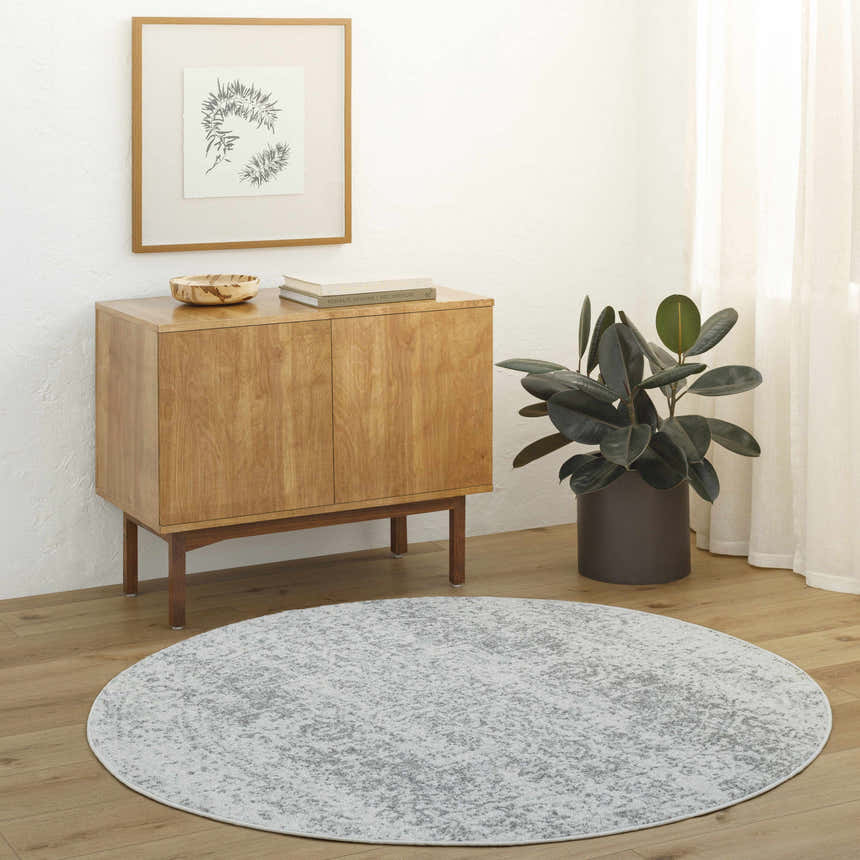 Entryway with round Livabliss Harput HAP-1024 rug in charcoal and gray, wood cabinet, plant, and neutral decor. Roomscene-Round