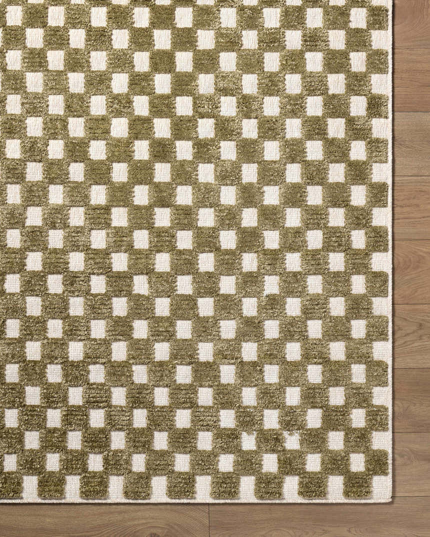 Close-up of the Anthea Olive Washable Area Rug. Olive and white checkerboard pattern with textured weave on wood floor. Corner