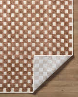 Close-up of the Anthea White Washable Area Rug showing brown and white checkerboard pattern and the rug's backing. Fold