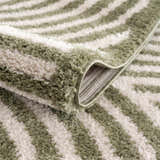 Close-up of the Allard Green Washable Area Rug showing its lime green and peach striped pattern and soft, textured pile. Fold