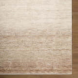 Close-up of the cream, dark brown, and gray textured Amaury Area Rug on a wood floor. Corner