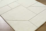 Close-up of the Alaina Area Rug. Ivory wool rug with a geometric pattern and charcoal lines on a wood floor. Corner