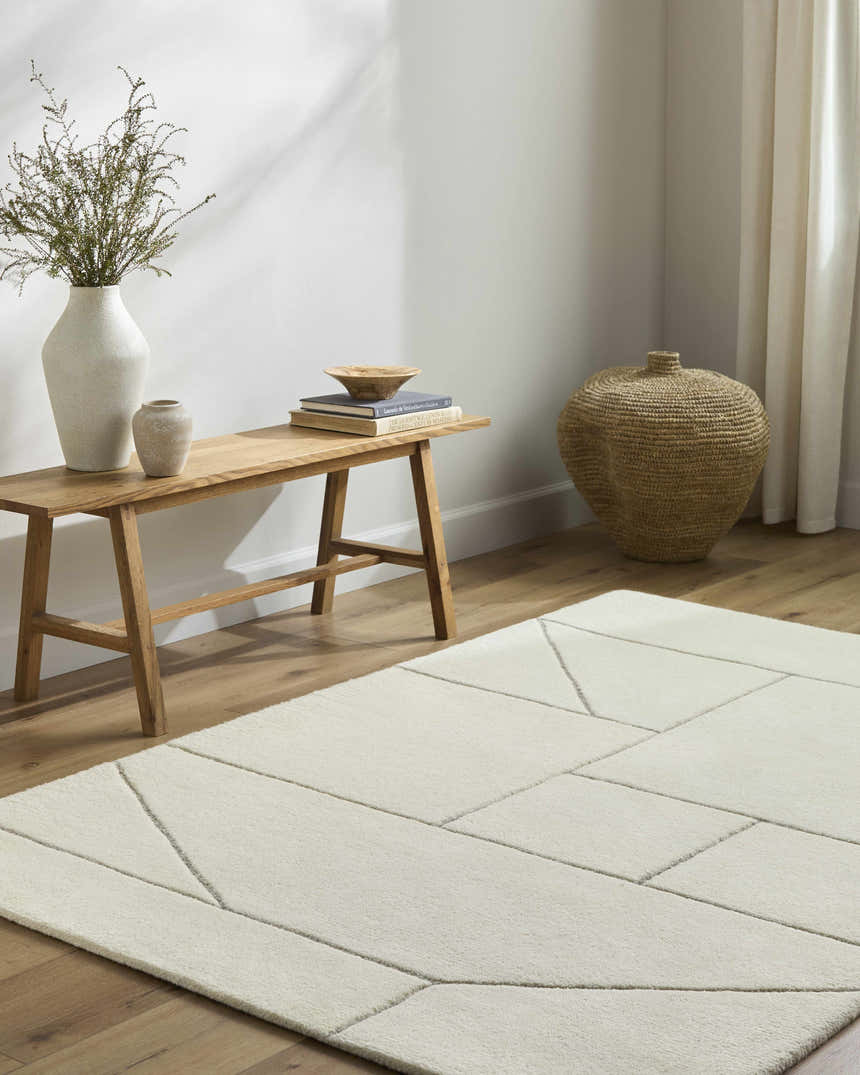 Neutral room scene with a light wood bench, woven basket, and the ivory Alaina Area Rug. Roomscene-Rectangle