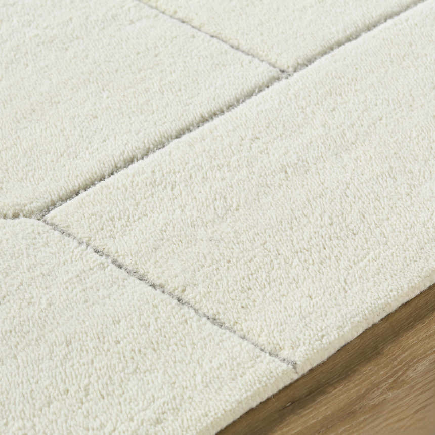 Close up of the hand-tufted Alaina Area Rug. Ivory wool rug with a subtle charcoal geometric pattern. Texture