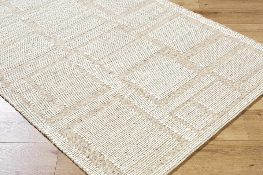 Close-up of the hand-woven Alayka Area Rug. Beige and light beige wool rug with a contemporary geometric pattern. Corner