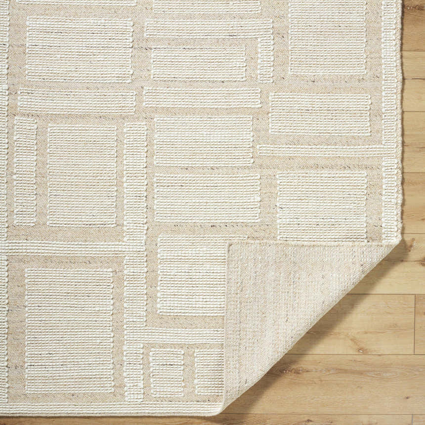 Close-up of the hand woven Alayka Area Rug. Beige wool rug with a contemporary geometric pattern. Fold