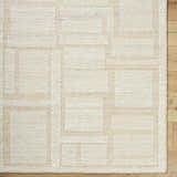 Close-up of the hand woven Alayka Area Rug. Beige and light beige wool rug with a contemporary geometric pattern. Corner