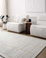 Living room scene with beige Alayka Area Rug, light neutral furniture, wood accents, and minimalist artwork. Roomscene-Rectangle