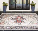 Entryway scene with a brick red and cream Halayhayin Premium Rug on black tile. Tall planters flank the glass door. Roomscene-Rectangle