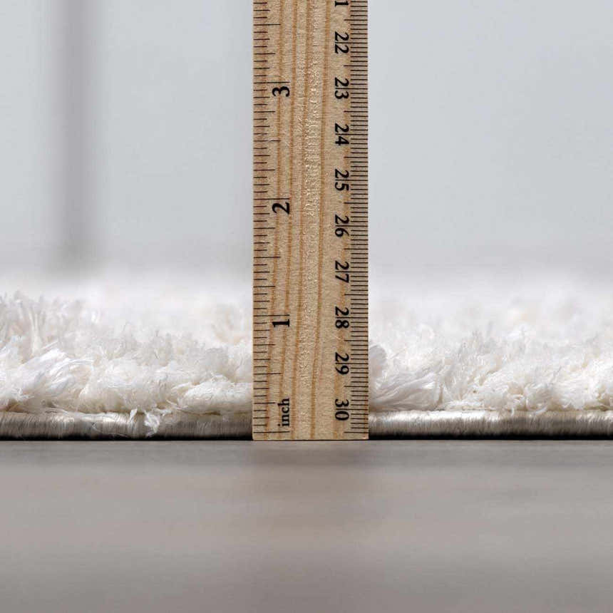 Close-up of the plush pile height of the cream Andia Plush Grid Rug with a ruler for scale. Pile