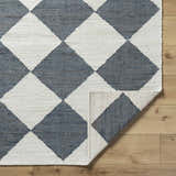 Close-up of Antho Handmade Vivir x LIVABLISS VVAT-2302 area rug with slate gray and ivory diamond pattern on wood floor. Fold