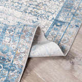 Close-up of the Hartsel Area Rug showing its blue, gray, and white traditional pattern and soft texture. Fold