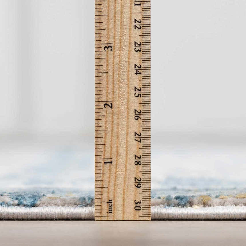 Close-up of Hartsel rug pile height. The rug has charcoal, blue, gray, and mustard colors. Pile