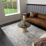 Living room scene with a blue and gray Hartsel Area Rug, brown leather sofa, and round coffee table. Roomscene-Rectangle