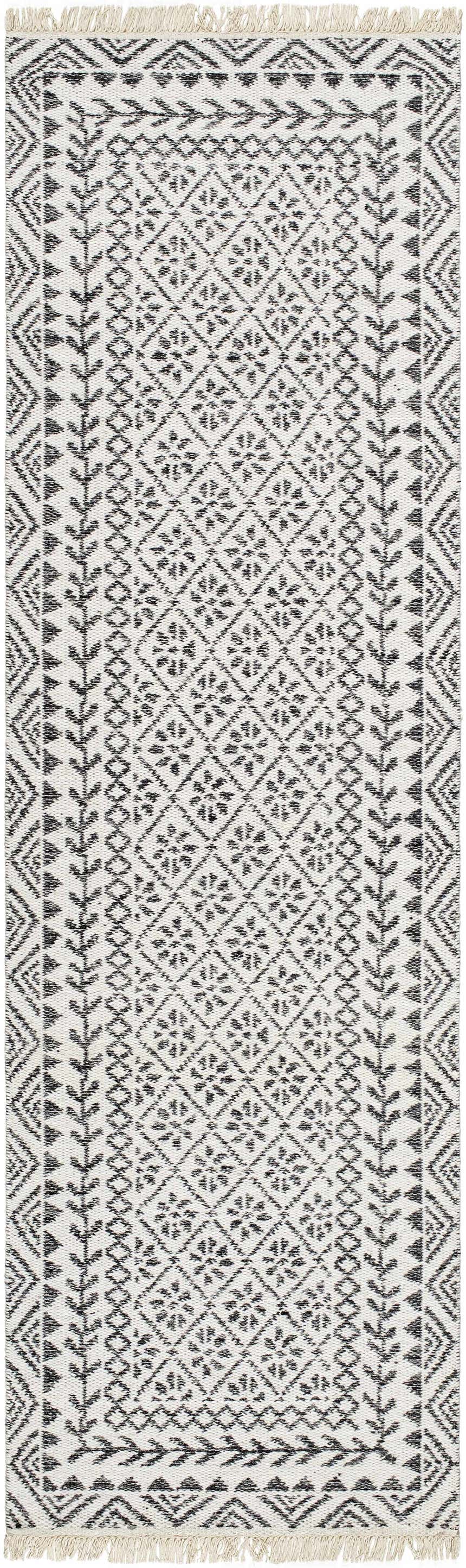 Close-up of the Hulda Area Rug. Hand-woven wool rug in lambswool and dark gray with a geometric farmhouse pattern and fringe. Design-Runner-268