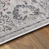 Close-up of the beige and gray Parkerfield Area Rug showing its traditional vintage pattern and soft texture. Corner