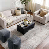 Living room scene with a neutral sofa, chair, and Ironwood Textured Luxe Rug in charcoal, gray, and brown tones. Roomscene-Rectangle