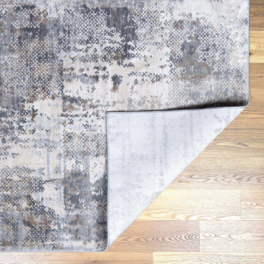 Close-up of the Ironwood Textured Luxe Rug. Charcoal, gray, light gray, brown, and taupe tones create a contemporary pattern. Fold